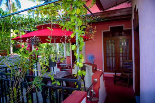 a house with a red umbrella and some plants at Tissa Rainbow Guest & Yala in Tissamaharama