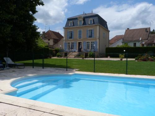 a large blue swimming pool in front of a house at Hôtel Restaurant du Cheval Blanc in Saint-Boil