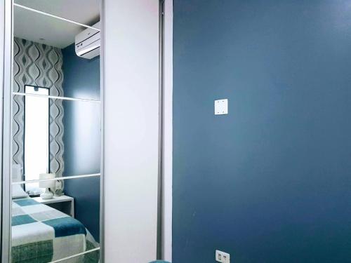 a bedroom with blue walls and a mirror at Mandakaru Residence Flats in Porto De Galinhas