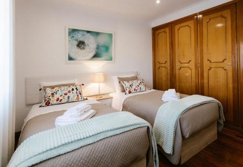 a bedroom with two beds and a wooden cabinet at Casa da Calçada II in Guimarães