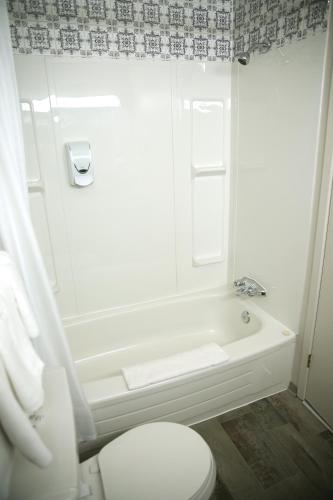 a bathroom with a white tub and a toilet at Motel Castille in Roberval