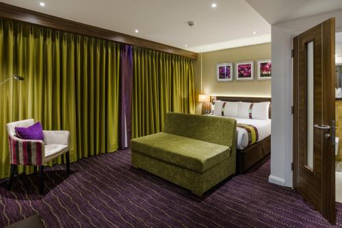 a hotel room with a bed and a chair at Holiday Inn London Watford Junction by IHG in Watford