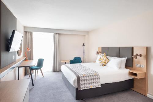 a hotel room with a bed and a desk and a tv at Holiday Inn Leicester City by IHG in Leicester