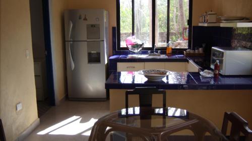 Hacienda San Jose Poniente Blue House في Hoctún: مطبخ مع ثلاجة وطاولة مع كرسي
