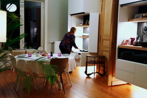 a woman standing in a kitchen with a table in a room at B&B AubergInn in Tessenderlo