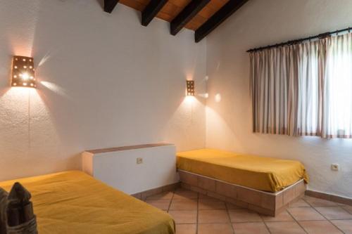 een slaapkamer met 2 bedden en een raam en verlichting bij Pedras Del Rei II in Tavira