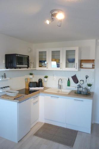 een keuken met witte kasten en een wastafel bij Studio -vue mer résidence Grand Cap in Villers-sur-Mer