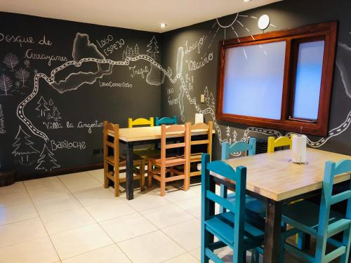 uma sala de jantar com uma parede de quadro com uma mesa e cadeiras em Hostel Olimpo House em San Carlos de Bariloche