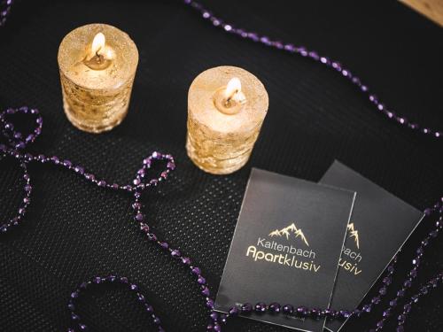 a table topped with two candles and a purple necklace at Apartklusiv Kaltenbach in Kaltenbach