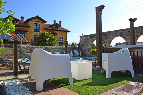 a patio with white chairs and a table in front of a house at Posada la Leyenda in Santillana del Mar
