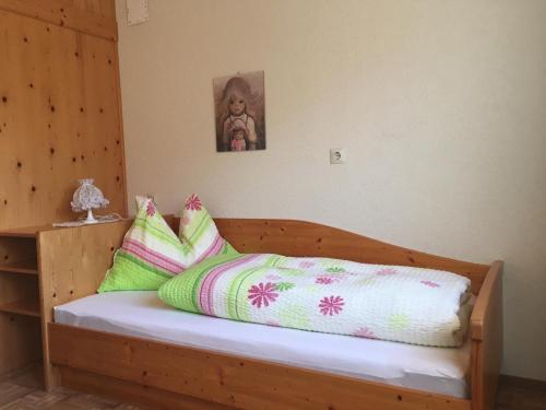a bed with green and pink pillows on it at Mitterbergerhof in Wiesen