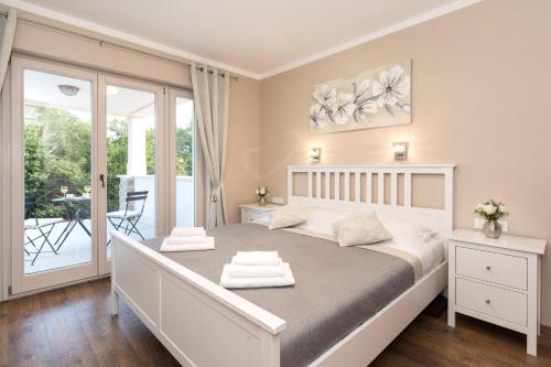 a white bedroom with a bed and a balcony at Villa Diamond - Muraj Krk in Kornić