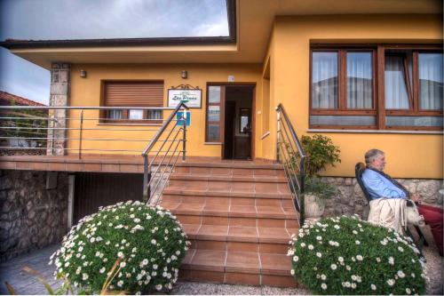 a man sitting on the stairs of a house at Hospederia Los Pinos in Llanes