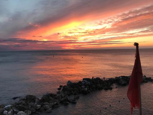 einen Sonnenuntergang über dem Meer mit einer Flagge am Strand in der Unterkunft CAST AWAY in Riomaggiore