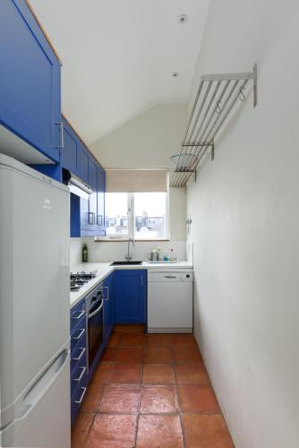 a kitchen with blue cabinets and a tile floor at Wix's Lane in London