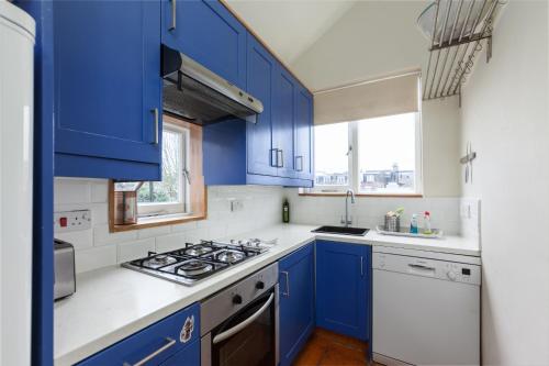 a blue kitchen with white counters and blue cabinets at Wix's Lane in London