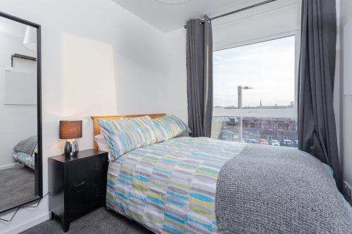ein Schlafzimmer mit einem Bett und einem großen Fenster in der Unterkunft Cosy and modern apartment HEART OF BELFAST in Belfast
