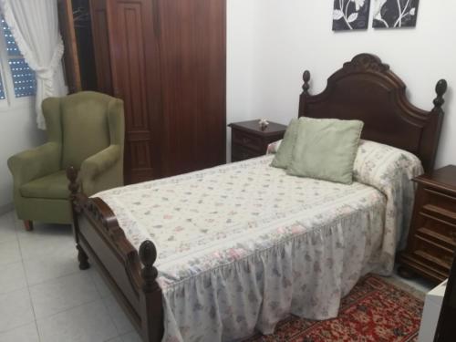 a bedroom with a bed and a green chair at Piso de Verano in O Grove