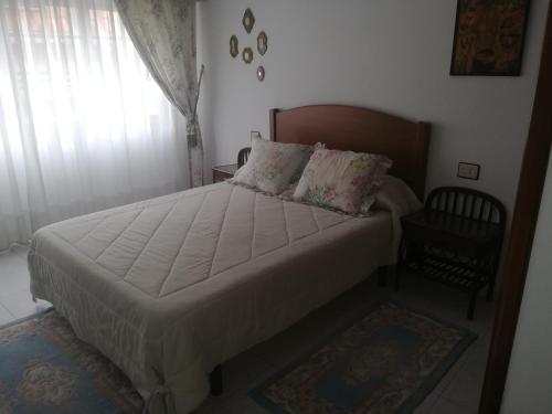 a bedroom with a large bed with white sheets and a window at Piso de Verano in O Grove