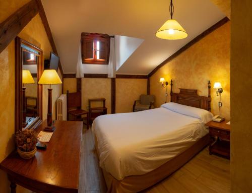 a bedroom with a large bed and a desk and a desk at Hotel Las Cancelas in Avila
