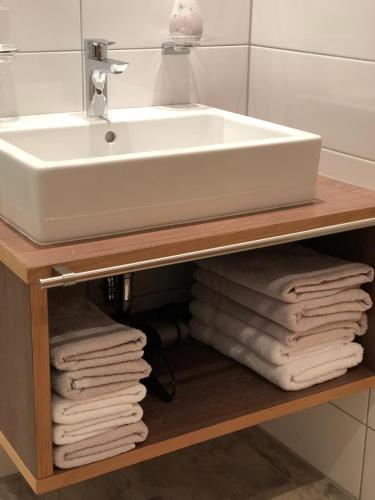 a bathroom sink on a wooden shelf with towels at Haus Lydia in See
