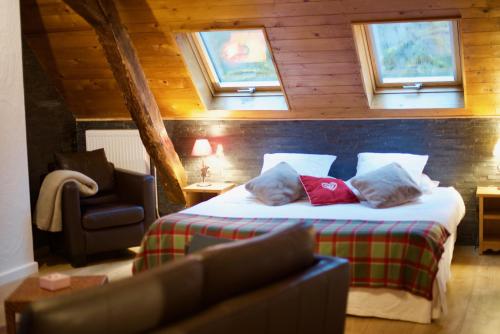 a bedroom with a bed and a chair and windows at Maison d'hôtes La Bageatière - Lac d'Aiguebelette in Lepin-le-Lac