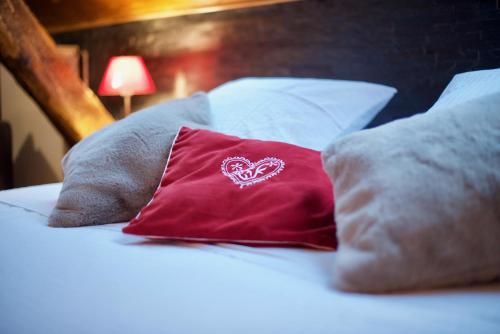 a red pillow with a heart on it sitting on a bed at Maison d'hôtes La Bageatière - Lac d'Aiguebelette in Lepin-le-Lac