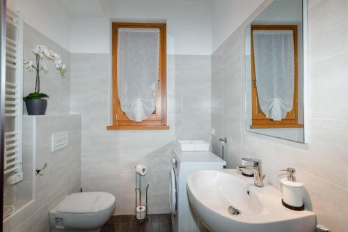 a white bathroom with a toilet and a sink at Lucy in Sirmione