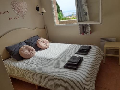 a bedroom with a bed with pink pillows and a window at résidence Bellevue in Roquebrune-sur-Argens