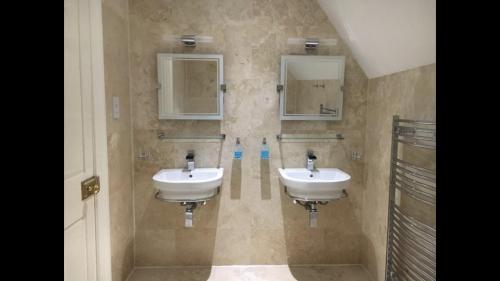 a bathroom with two sinks and two mirrors at Dundee Beds in Dundee