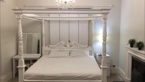 un letto a baldacchino bianco in una camera da letto con specchio di Dundee Beds a Dundee