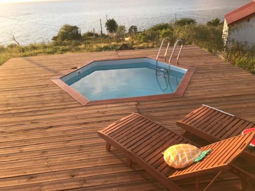 a wooden deck with a swimming pool and two chairs at Bungalow Mathilde Bis- Non fumeur in Bouillante
