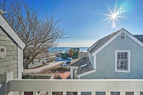 a house with a white fence and the ocean in the background at Ocean View and Beach Access Cape Cod Townhome in Mashpee