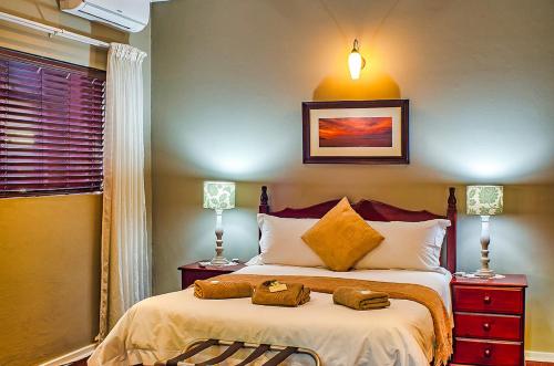a bedroom with a bed with two night stands and two lamps at Amper Bo Guest House in Pretoria