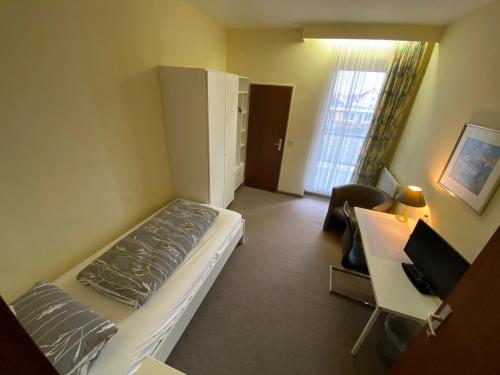 a small room with a bed and a desk and a chair at HoteLPension am Thermalbad in Bad Nenndorf