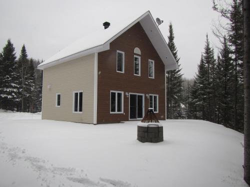 a house with snow in front of it at domaine de la vallee in Sainte-Rose-du-Nord