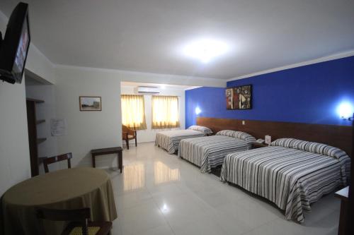 una camera d'albergo con tre letti e un tavolo di Hotel Oriente a Veracruz