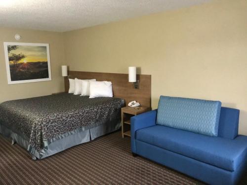Pokój hotelowy z łóżkiem i niebieskim krzesłem w obiekcie Days Inn By Wyndham Lexington-Columbia w mieście Lexington