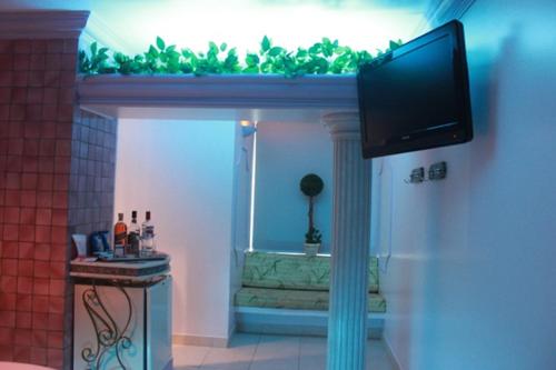 a living room with a flat screen tv on a wall at Motel Le Plaisir in Salvador