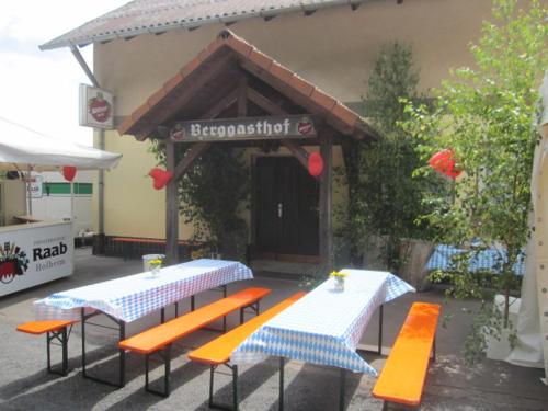 two tables and benches in front of a restaurant at Berggasthof Bayernturm in Zimmerau