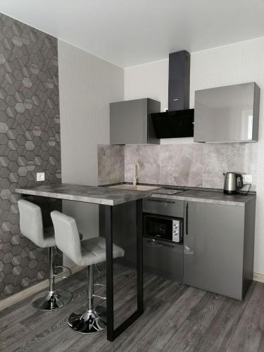 a kitchen with a table and two bar chairs at Solo Apartment Kamenskaya in Kyiv