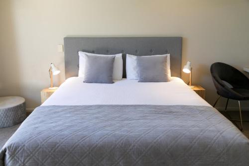 a bedroom with a large bed with white sheets and pillows at Alpine Lake Motel in Taupo