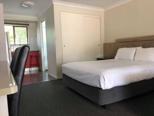 a bedroom with a bed and a chair in it at Hervey Bay Motel in Hervey Bay