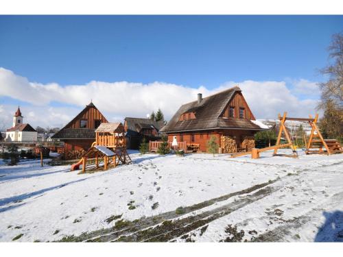 a snow covered yard with houses and a playground at Rekreačné chalupy in Liptovský Trnovec