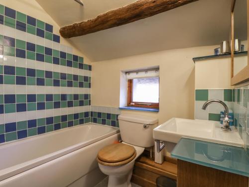 a bathroom with a toilet and a tub and a sink at Barn Roost in Uldale