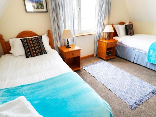 a bedroom with two beds and two lamps and a window at Dartmoor Valley Lodge in Gunnislake
