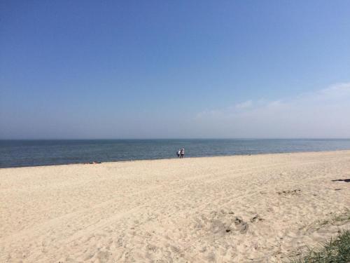 a person standing on a sandy beach near the ocean at Deichkrone in Horumersiel