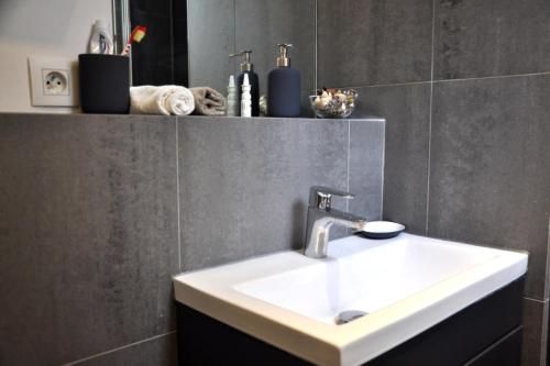 La salle de bains est pourvue d'un lavabo blanc et d'un mur gris. dans l'établissement Charming Apartment In Boulogne, à Boulogne-Billancourt