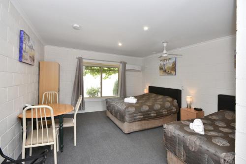 Pokój hotelowy z 2 łóżkami, stołem i biurkiem w obiekcie Inglewood Motel and Caravan Park Victoria w mieście Inglewood