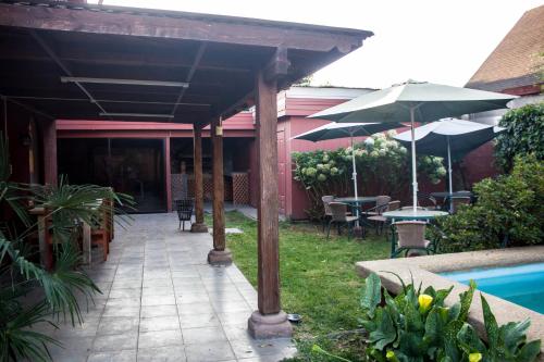 a patio with tables and umbrellas next to a pool at Hostal Helios in Los Ángeles